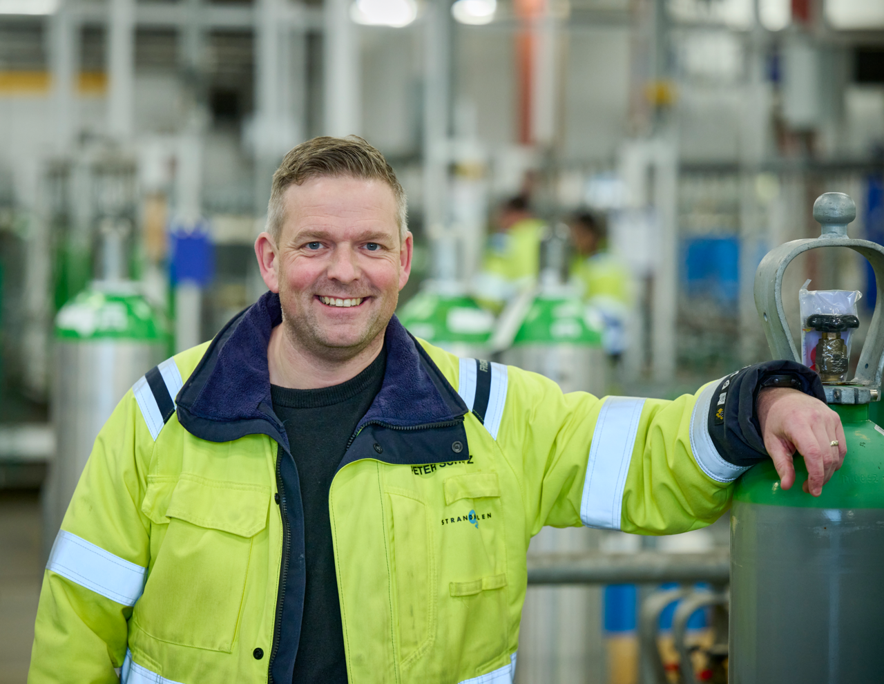 Glade medarbejdere på fabrik mellem flasker snakker om arbejdsplads. Sikkert arbejde i gas industri. 